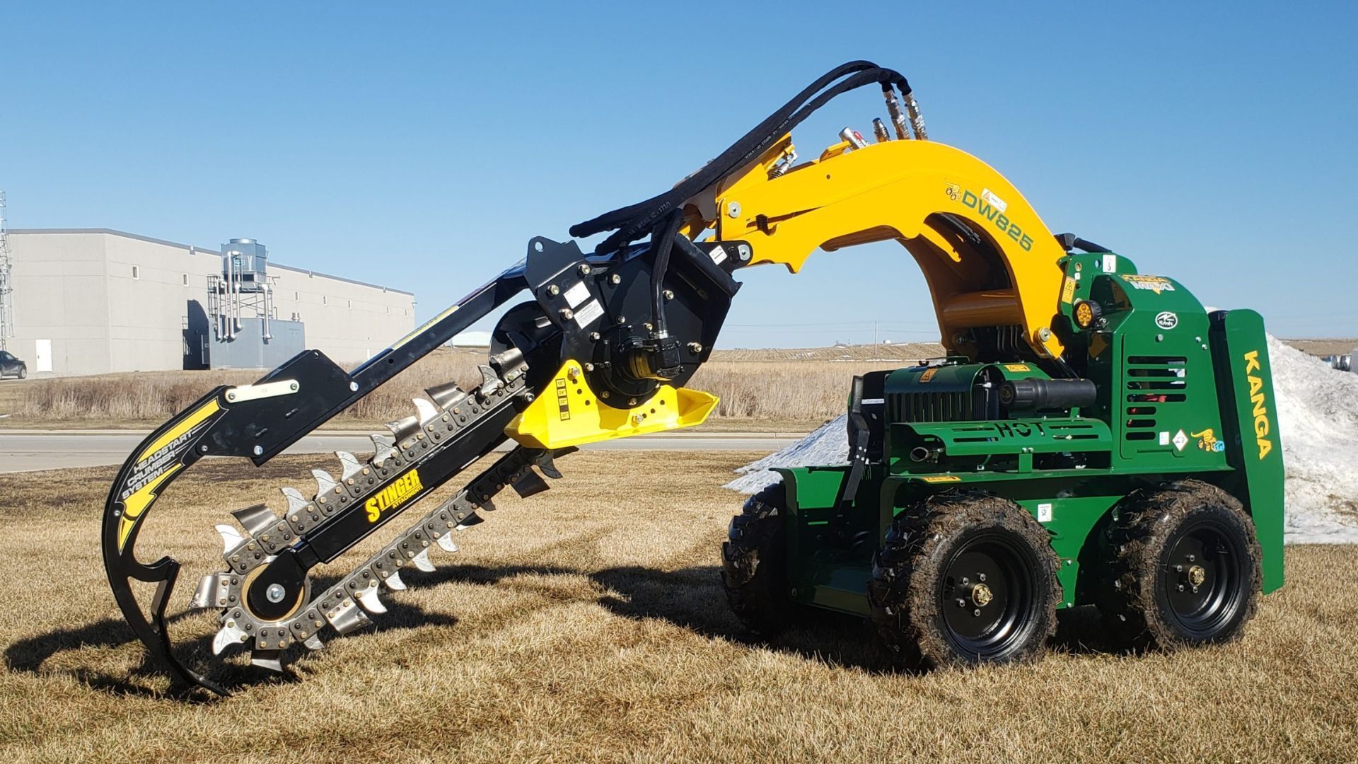 Green skid steer lifting a yellow tree shearing attachment in a field