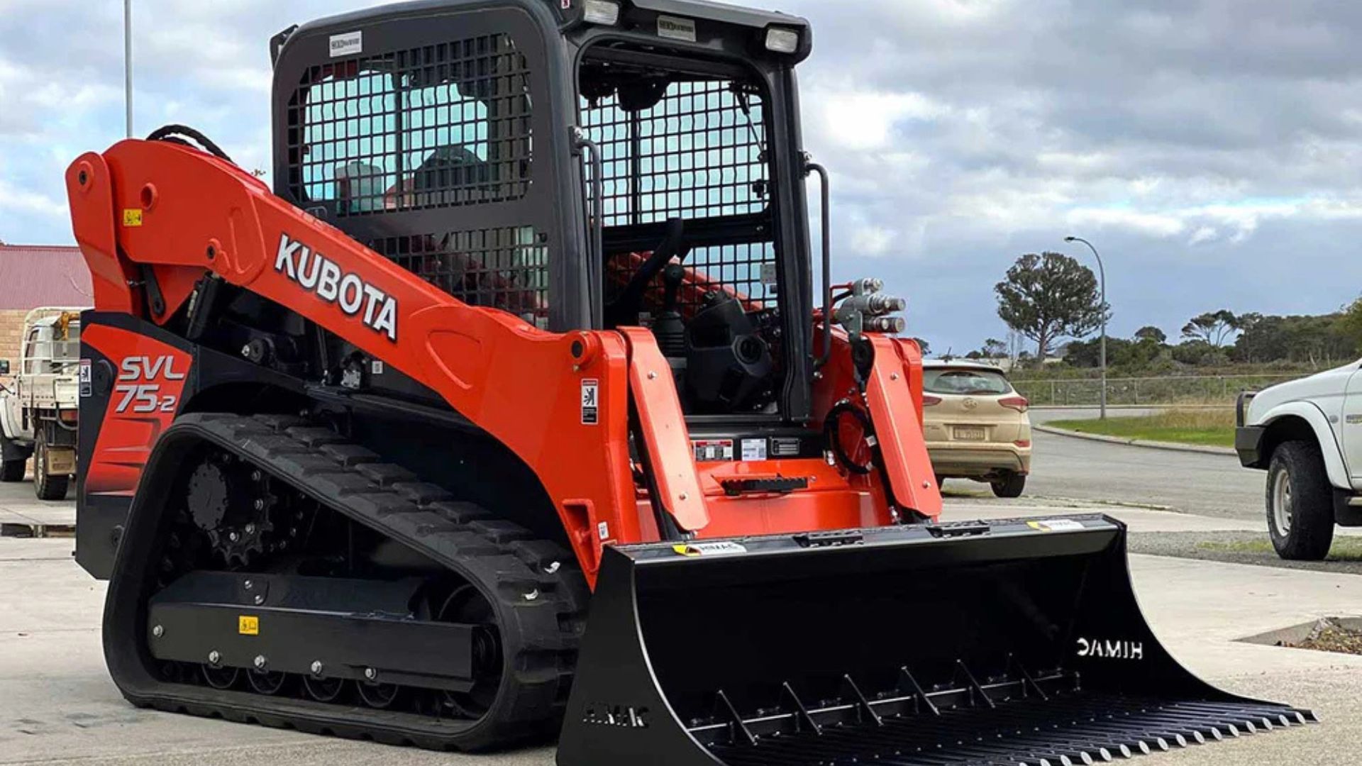 Red Kubota compact track loader with front bucket parked outdoors on a lot