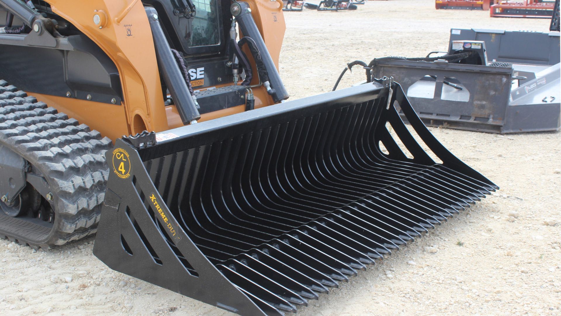 Black skid-steer bucket attachment with toothed edge on a construction site
