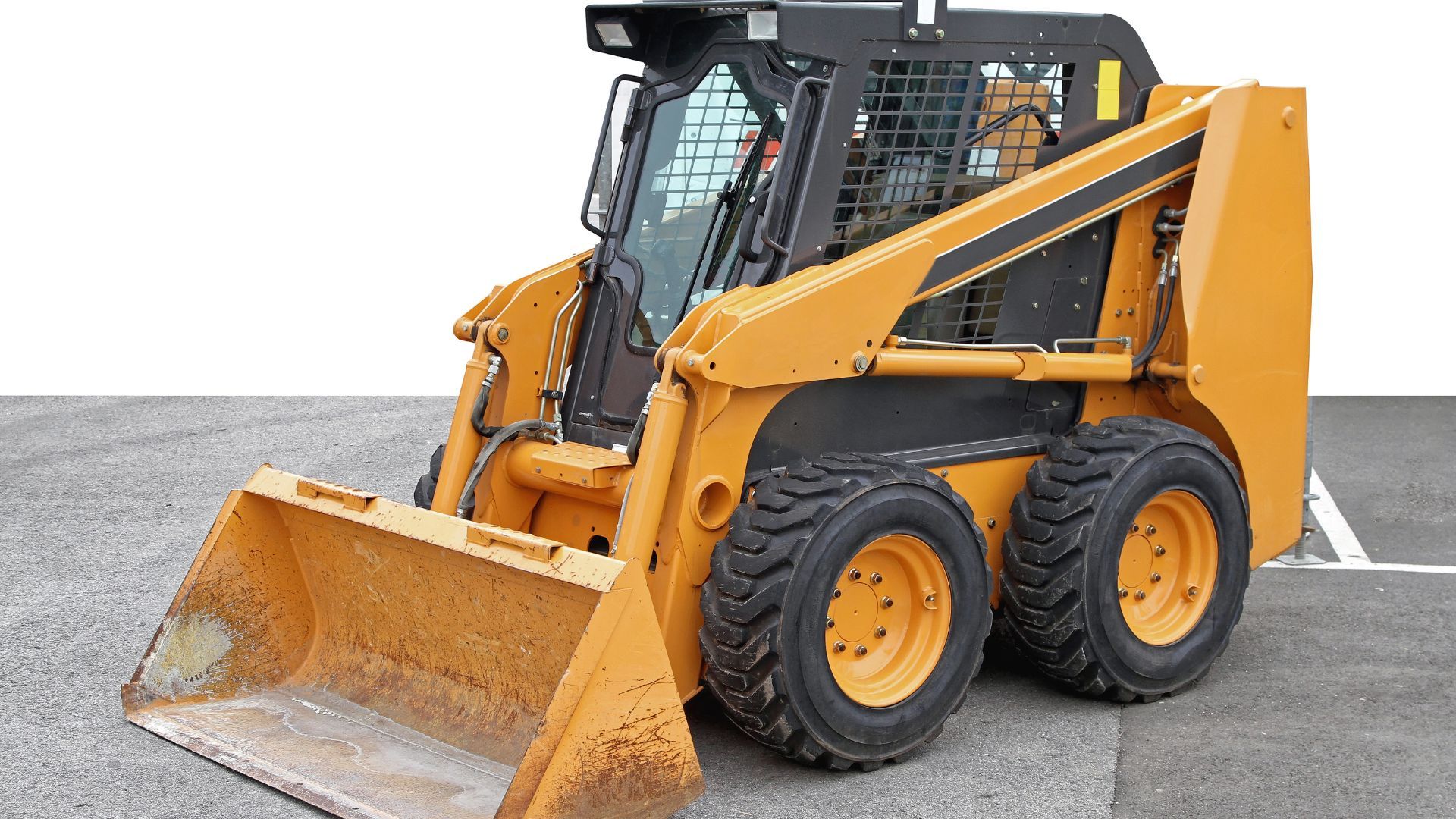 Yellow skid-steer loader with front bucket parked on pavement