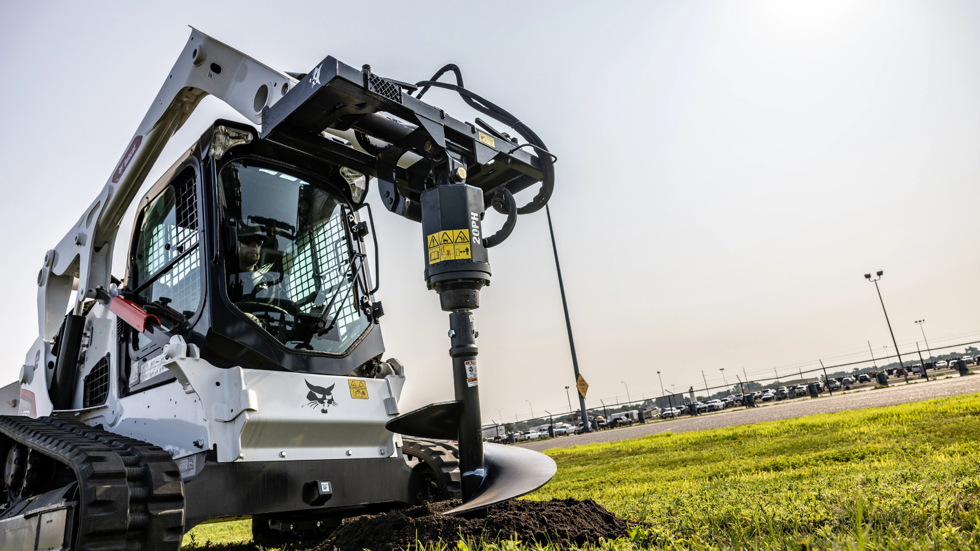 White agricultural machine with a front-mounted attachment working in a field under a cloudy sky