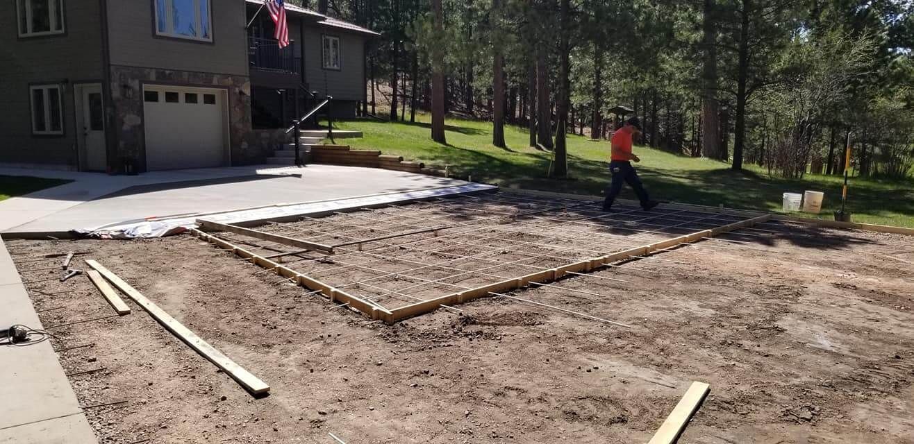 A man is working on a concrete driveway in front of a house.