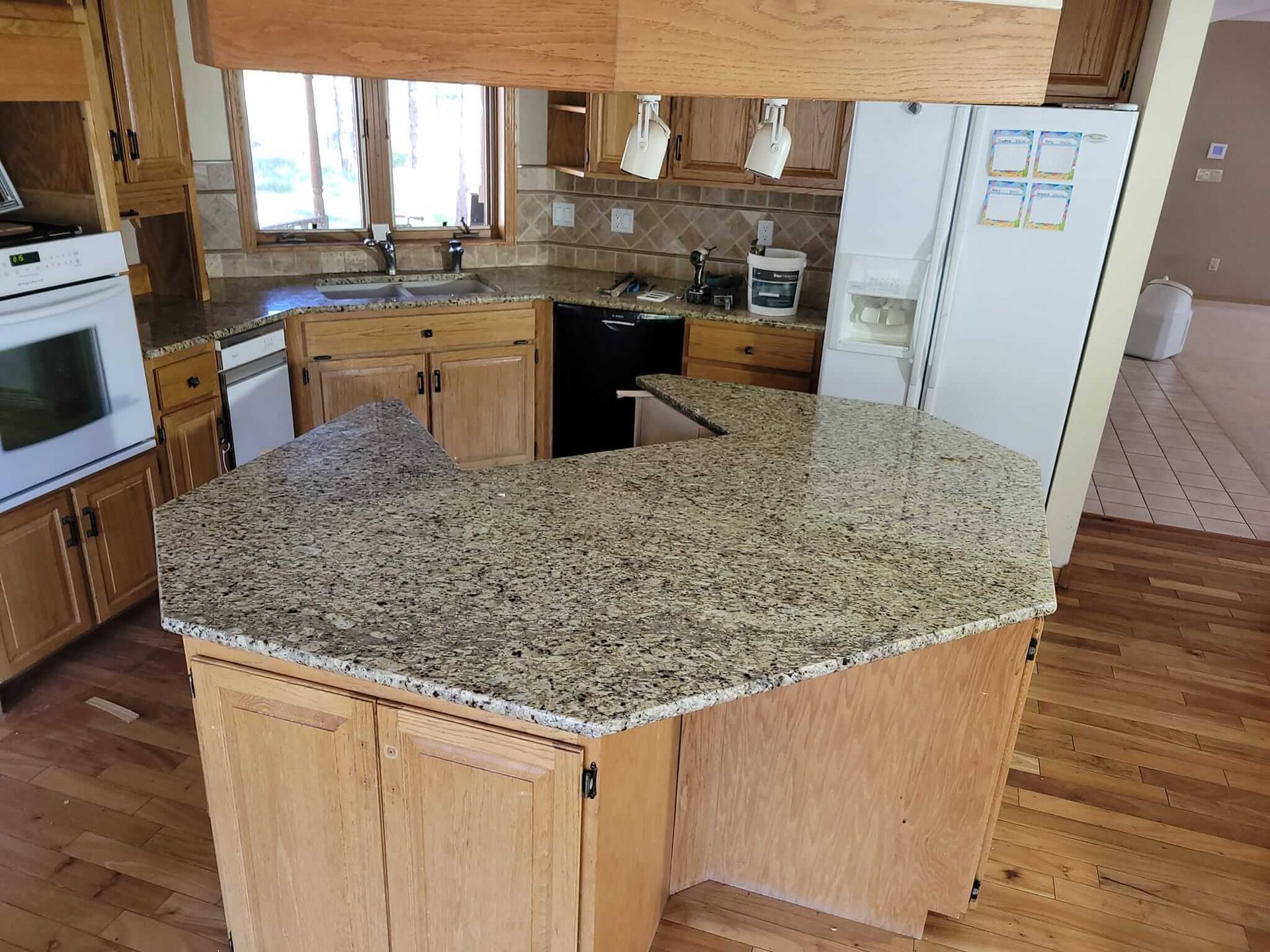 Kitchen with light wood cabinets, granite countertops, and a white refrigerator.