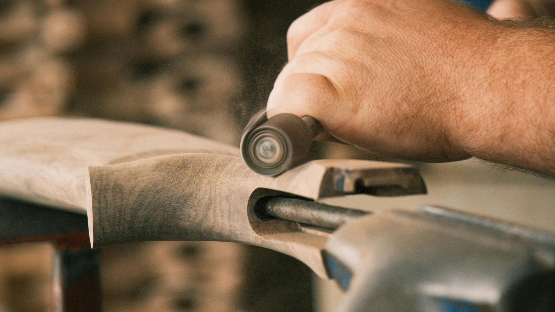 Hand sanding a wooden object with a small sanding block, close-up in a workshop