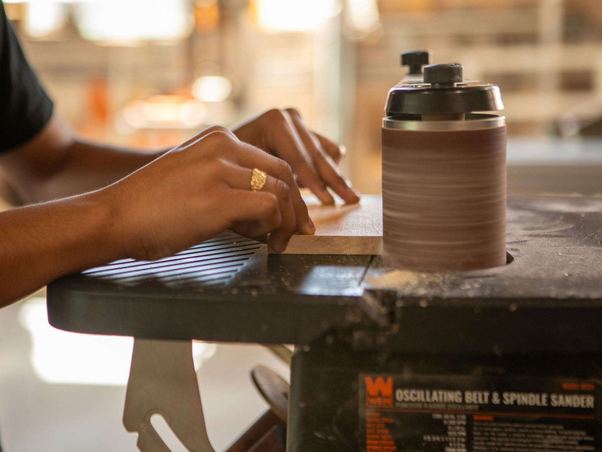 Hands typing on a laptop beside a brown water bottle in a sunlit café workspace