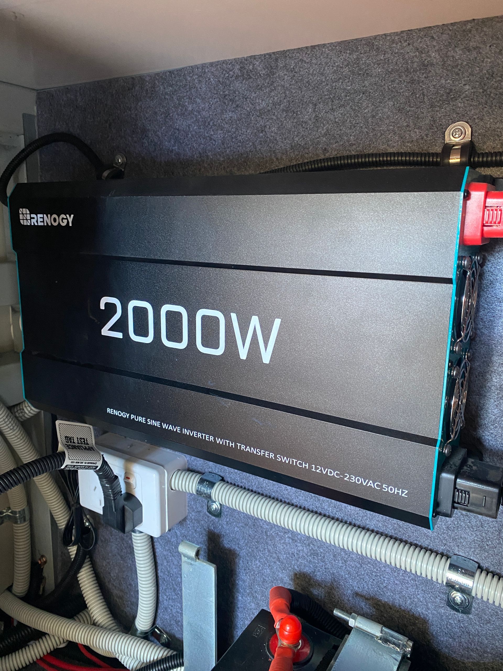 A 2000W inverter mounted in a vehicle, with wiring and battery connections visible.
