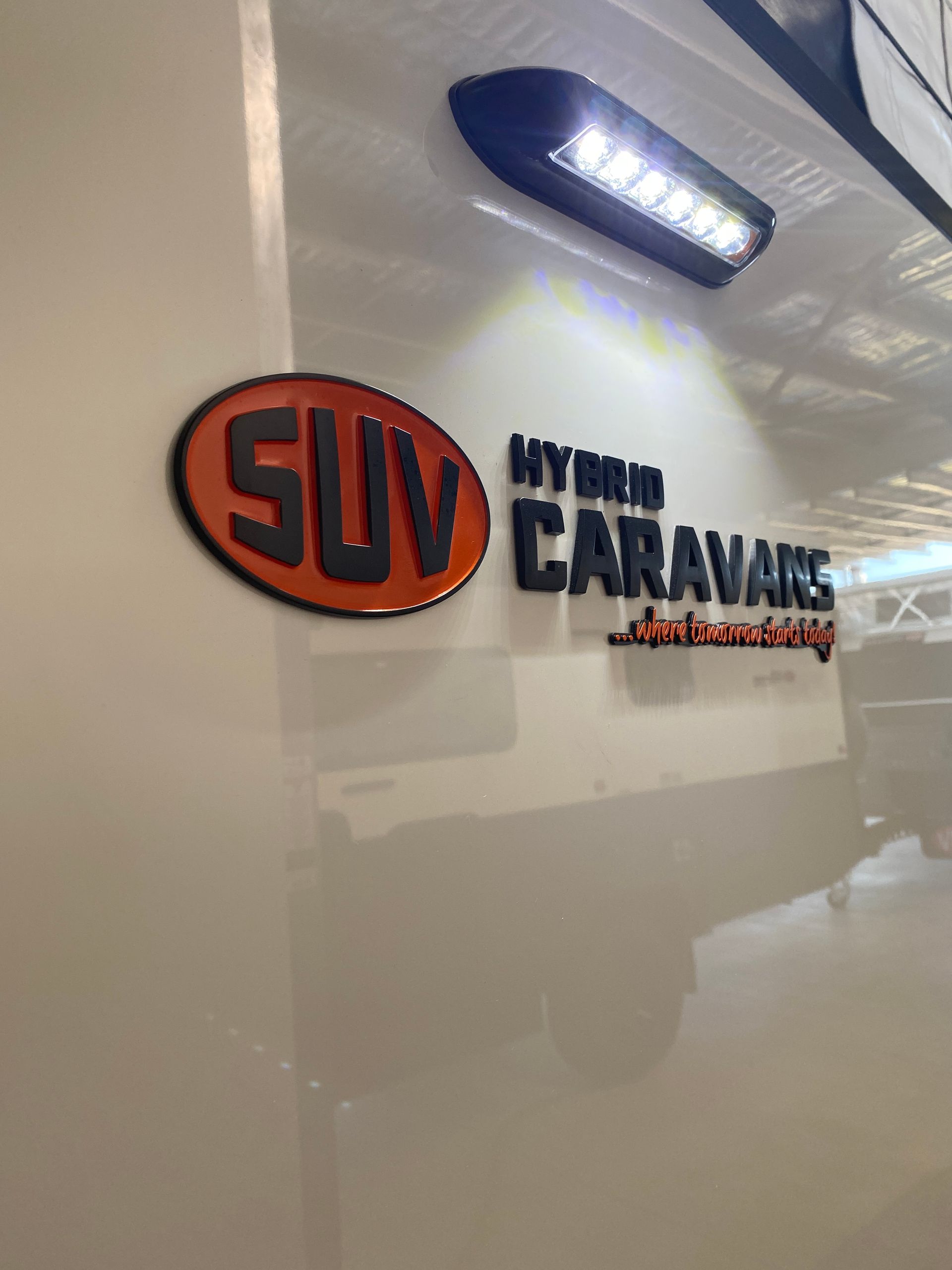 SUV caravan logo with "MY VAN CARAVANS" text on white panel, illuminated by LED light.