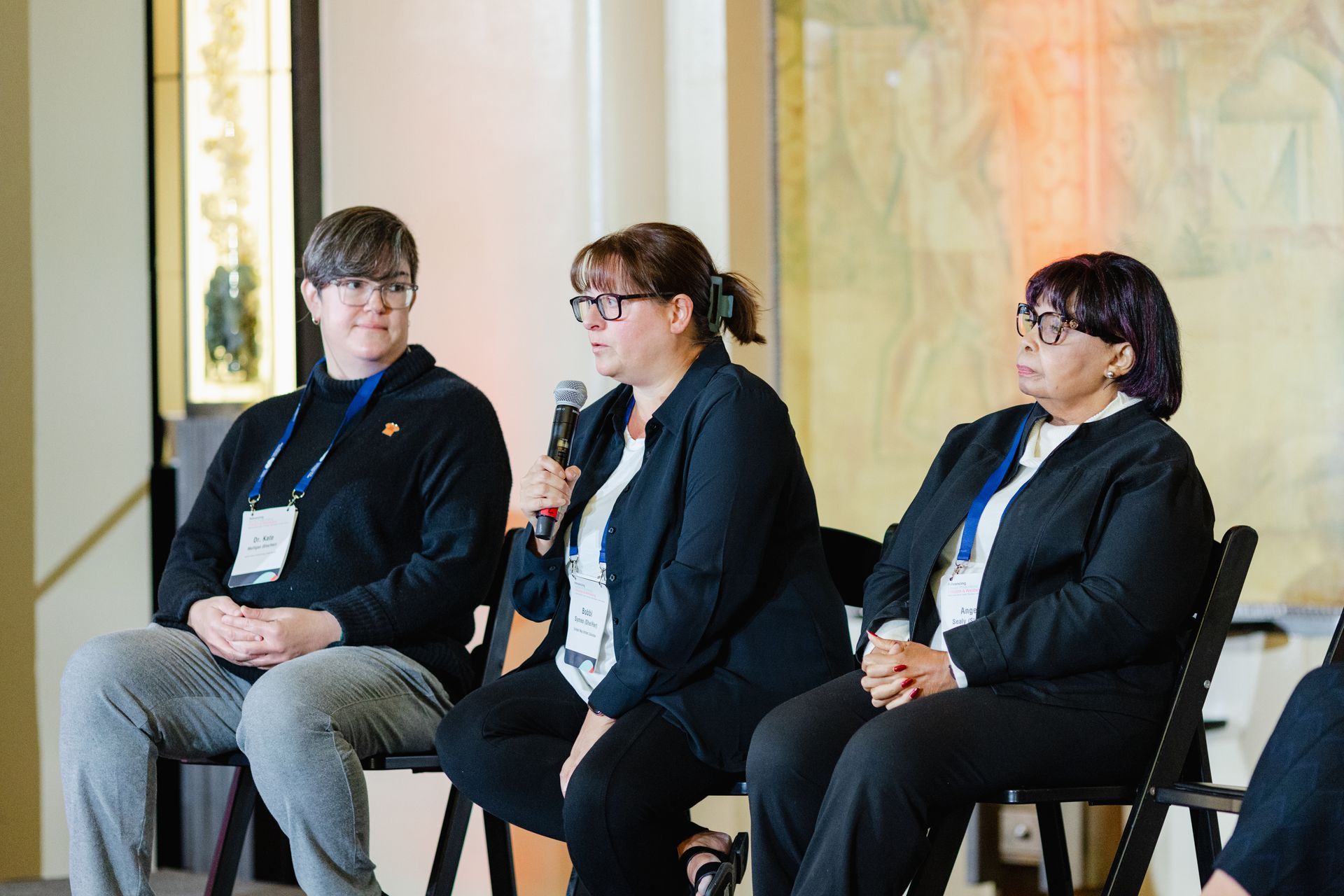 Trois femmes sont assises sur des chaises et parlent dans des microphones.