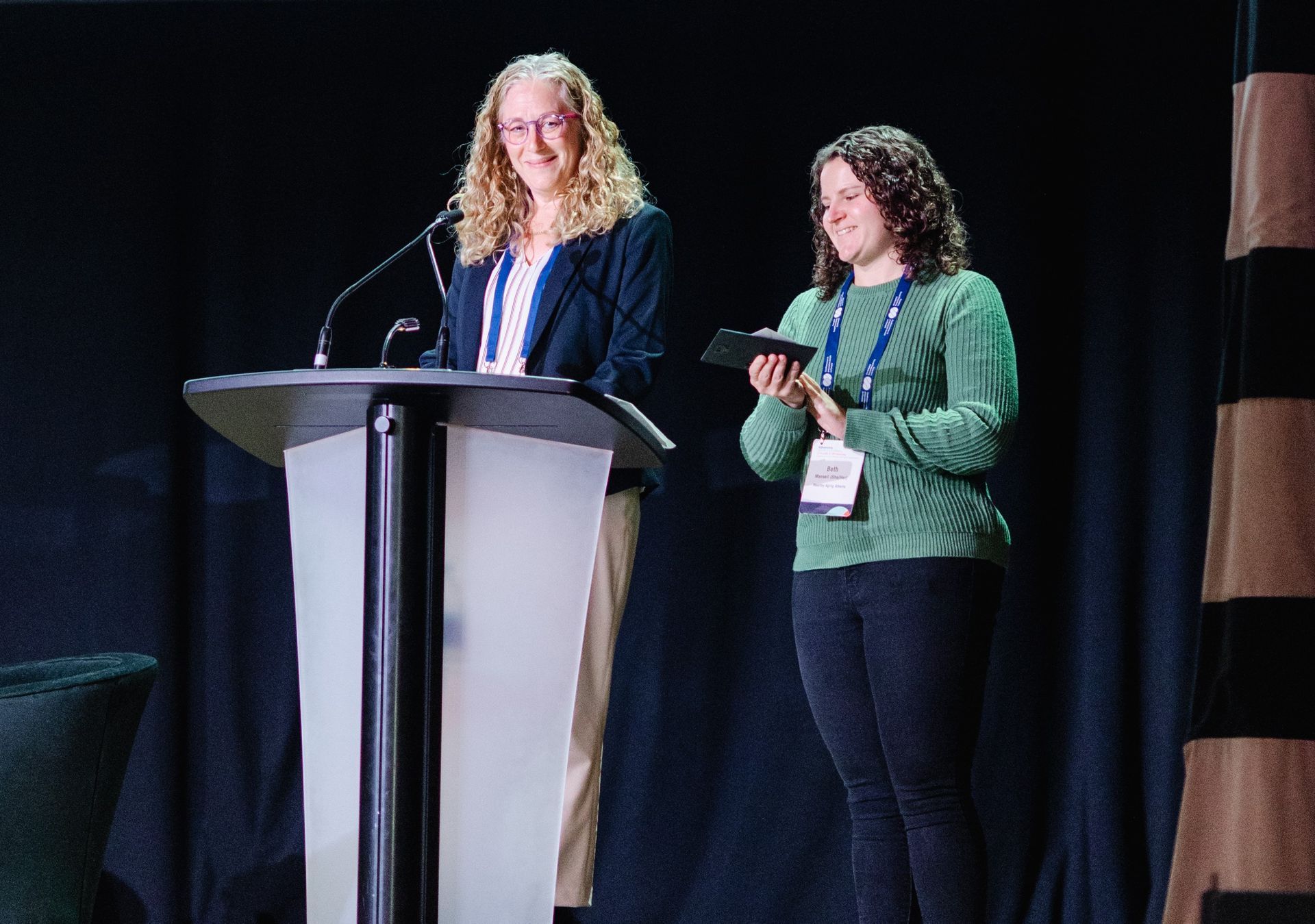 Deux femmes se tiennent sur un podium et font une présentation