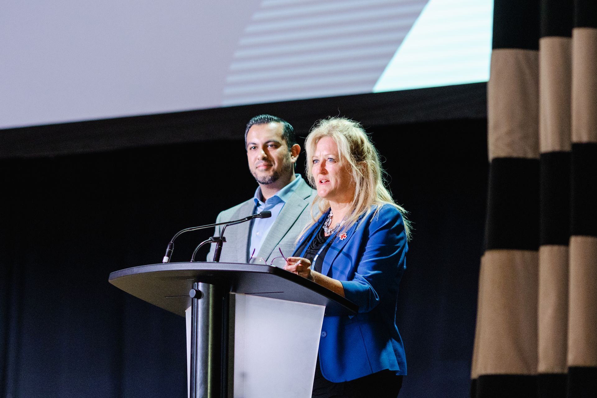 Un homme et une femme se tiennent sur un podium et prononcent un discours.