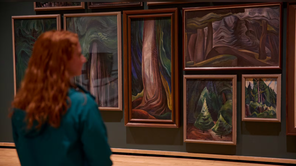 A woman is looking at paintings in a museum.