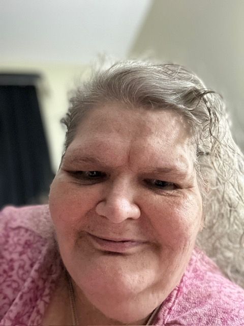 A woman in a pink shirt is smiling for the camera.
