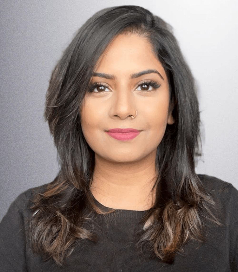 A woman with long hair and pink lipstick is wearing a black shirt.