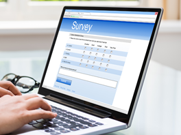 A person is typing on a laptop with a survey on the screen