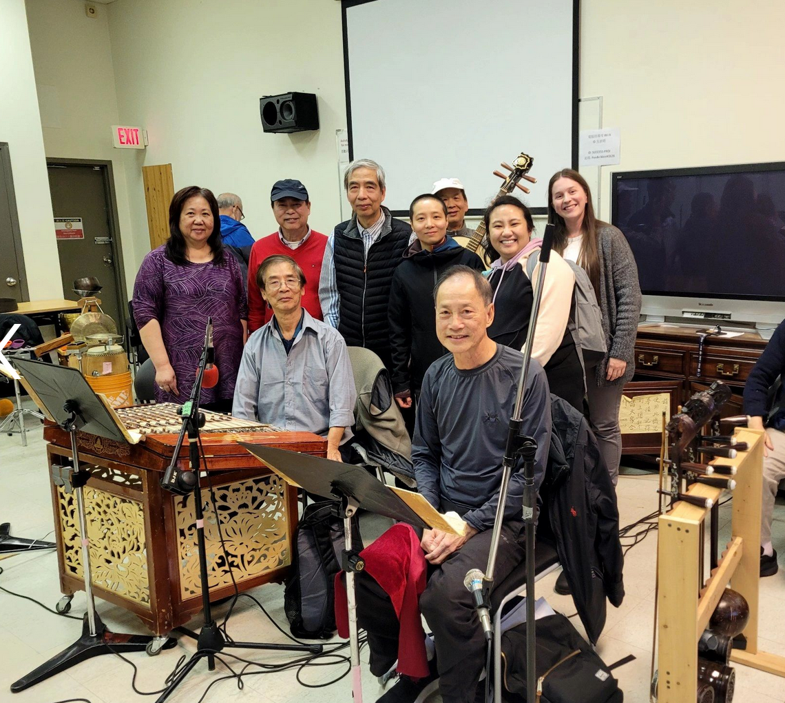 A group of people are posing for a picture in a room with instruments.