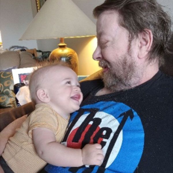 Un homme tient un bébé portant un t-shirt sur lequel est écrit les Rolling Stones