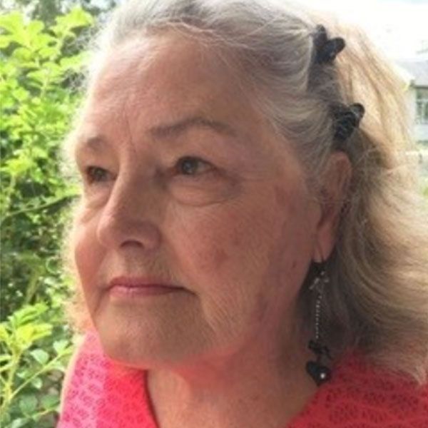 Un gros plan du visage d'une femme portant une chemise rose et des boucles d'oreilles.
