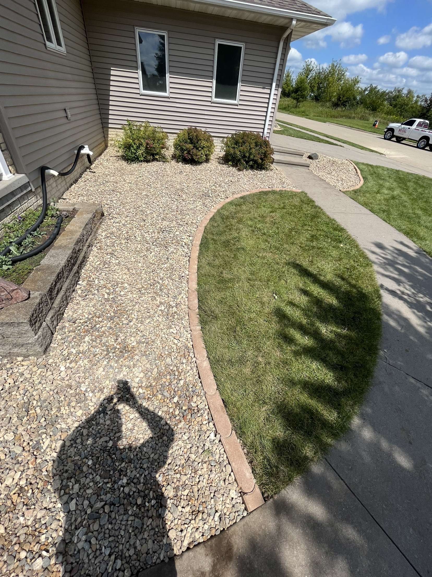 A shadow of a person is cast on a sidewalk in front of a house.
