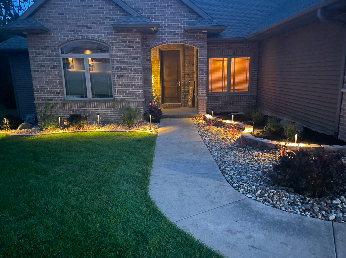 A brick house with a walkway leading to the front door at night.