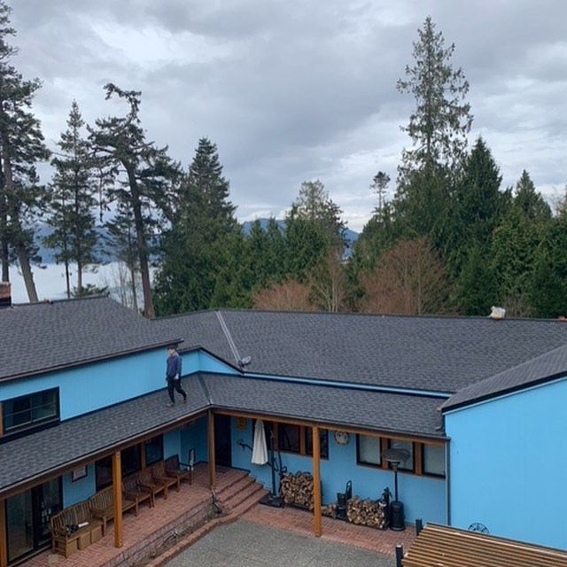 A man is standing on the roof of a blue house
