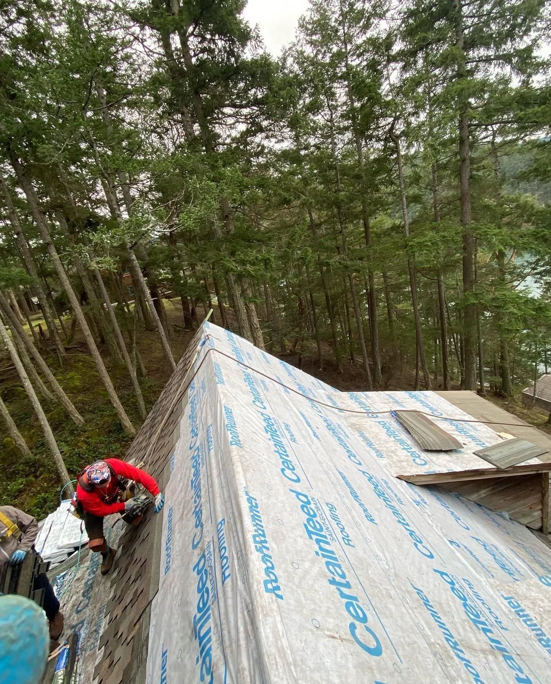 A man is working on a roof in the woods.