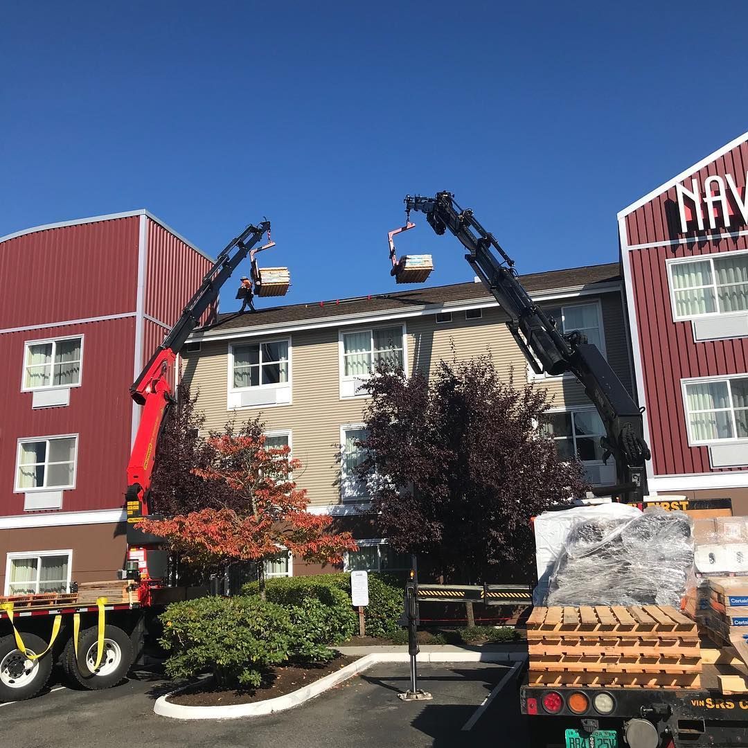 A crane is lifting a box on top of a building.