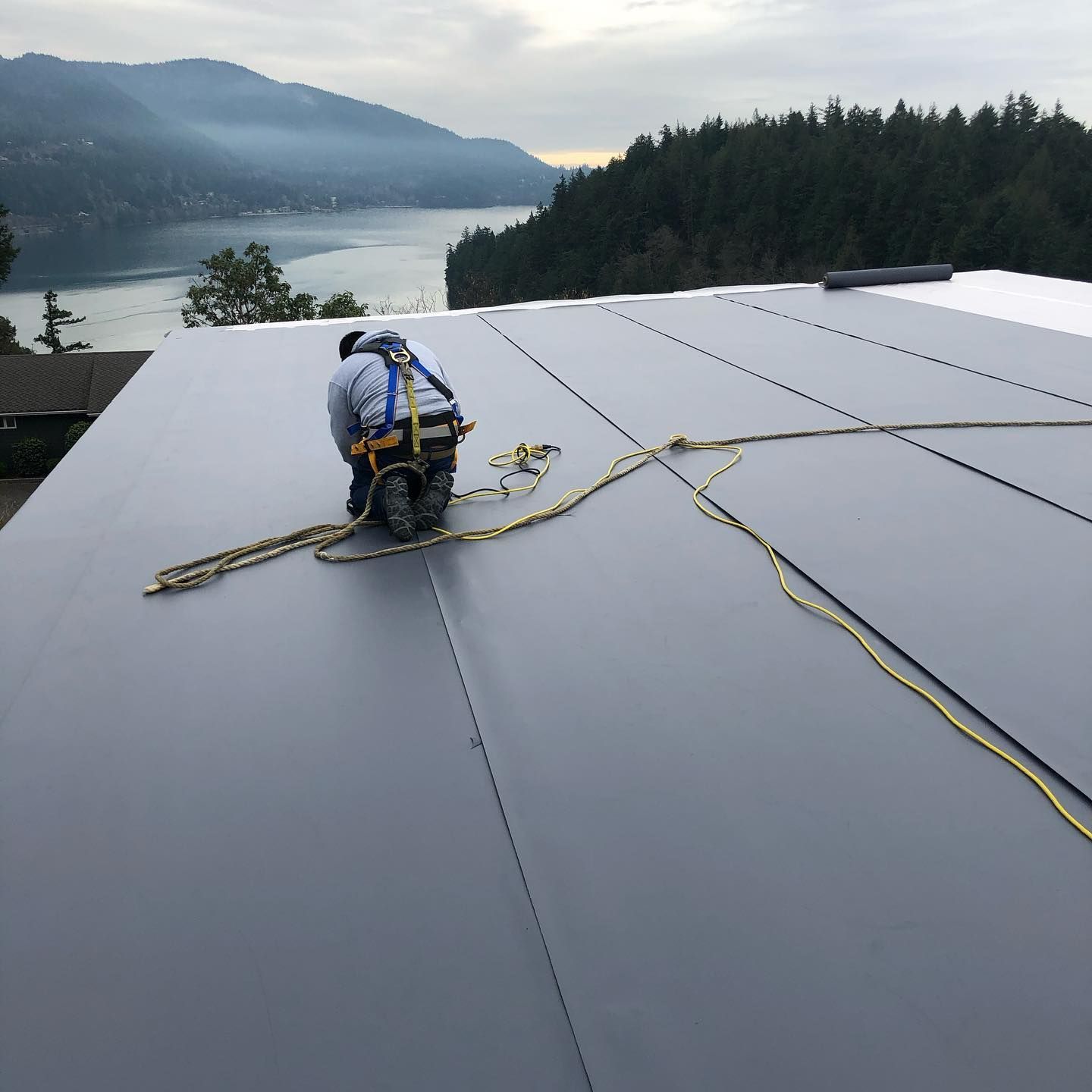 A man is working on a roof with a lake in the background