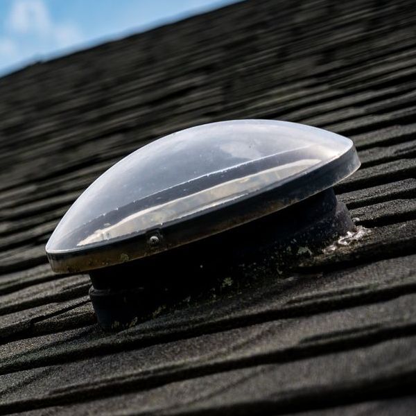 A clear dome skylight is sitting on top of a roof.