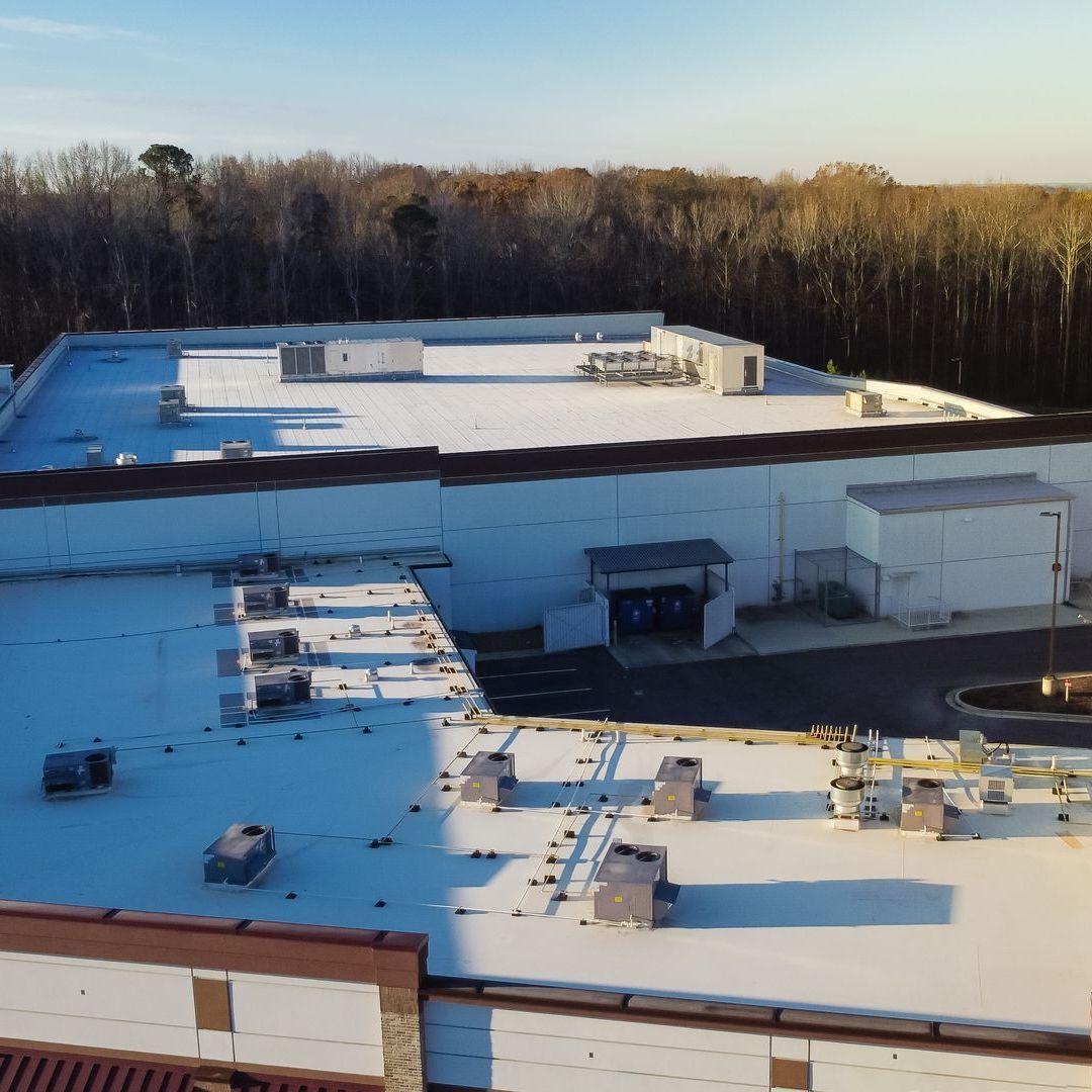 An aerial view of a large commercial building with a white roof