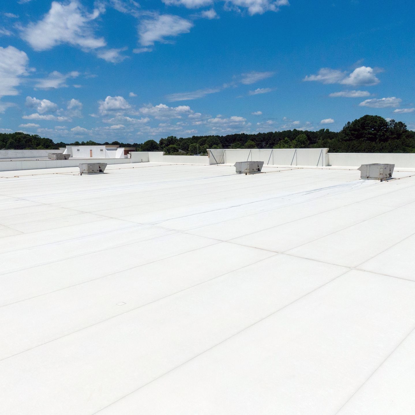 A large white commercial flat roof with a blue sky in the background.