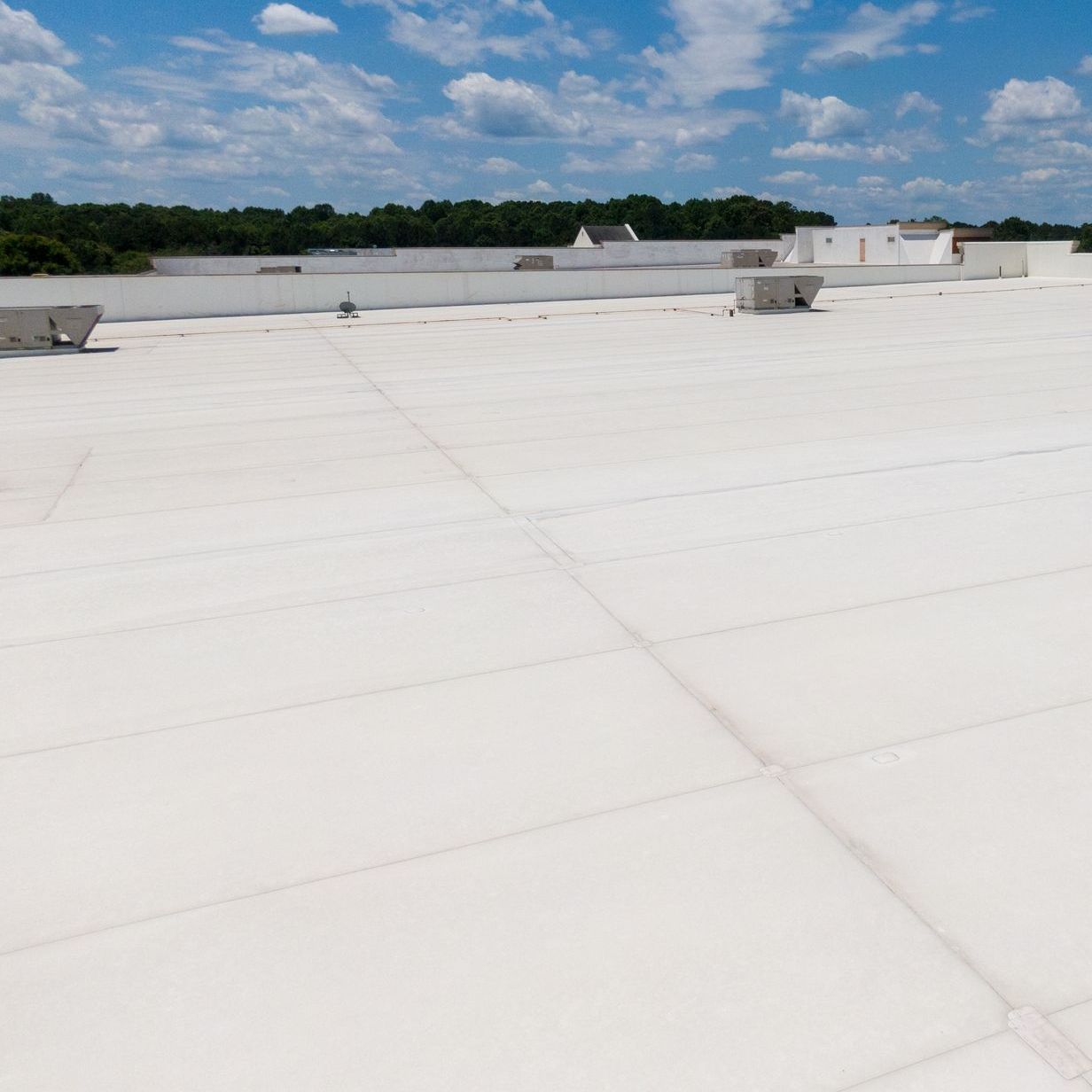 A large commercial white flat roof with a blue sky in the background.