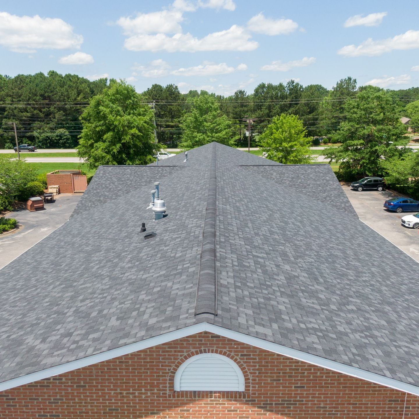 An aerial view of a brick building with a black roof