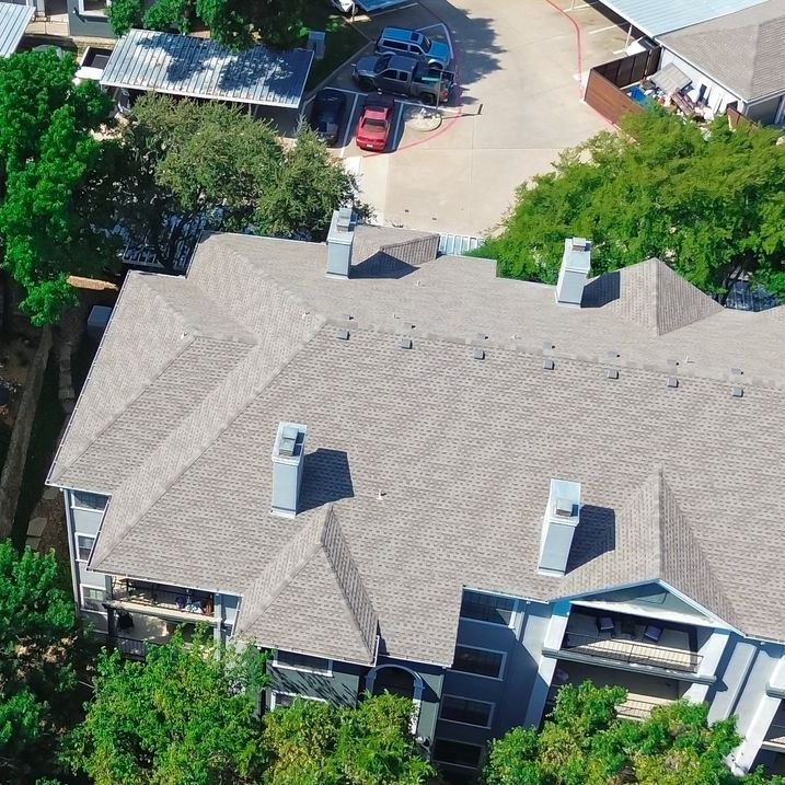 An aerial view of a multifamily building with a gray shingle roof
