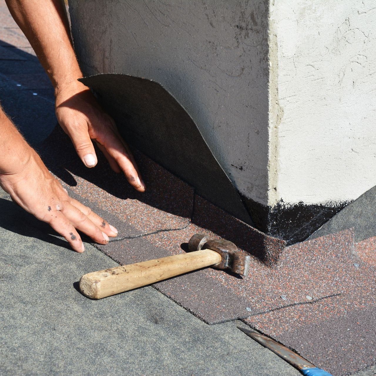 A person is working on chimney flashing with a hammer next to them