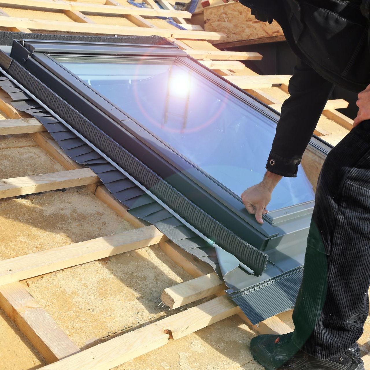 A man is installing a custom skylight on a roof