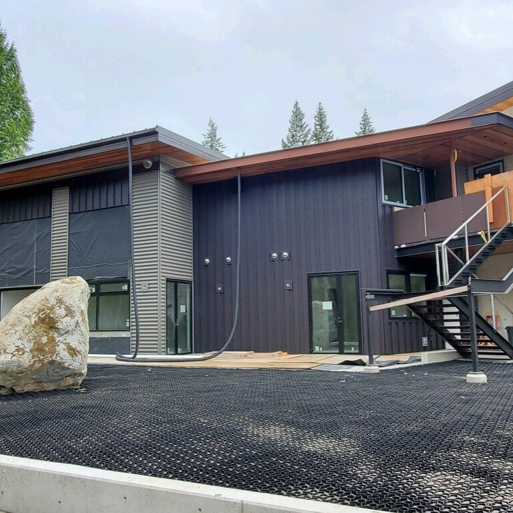 A large house with stairs and a large rock in front of it.