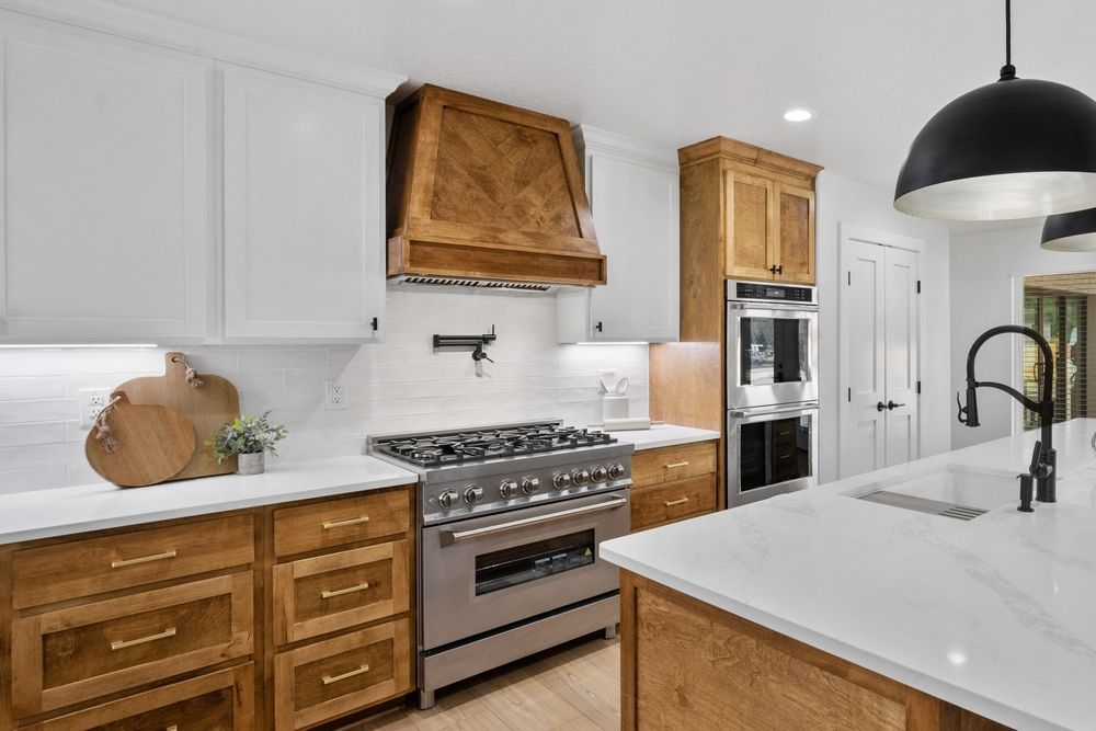 Bright modern kitchen with white countertops, wood cabinets, stainless stove, and large island sink