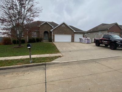Suburban brick houses with driveway, mailbox, and a black truck parked by the garage.