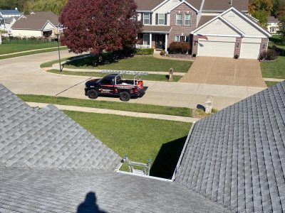 Black pickup truck parked on a suburban street in front of a brick house with a white garage