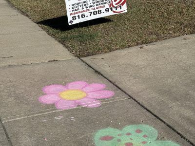 Sidewalk with pink and green chalk flower drawings near a yard sign