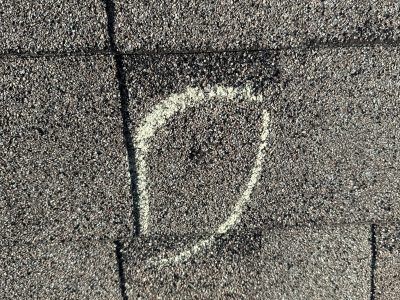 White chalk mark on dark asphalt pavement near a seam in the road.