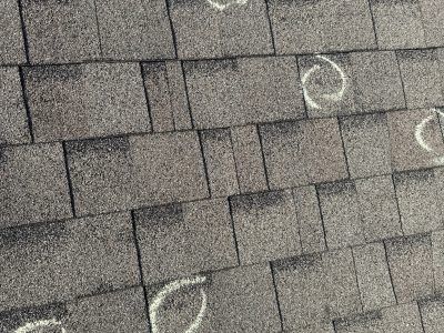 Gray shingled roof with white chalk markings on several shingles