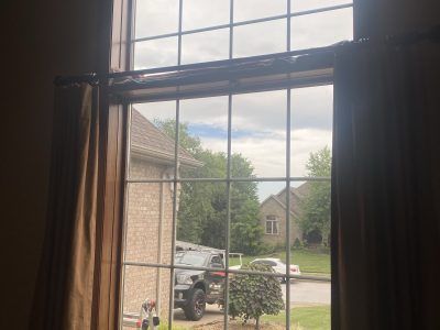 View through a window to a suburban street, parked truck, and neighboring houses on a cloudy day