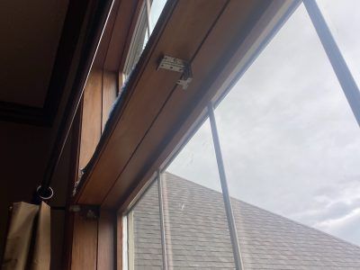 Interior view of a window with wooden trim, showing a cloudy sky and roof outside.