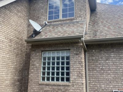 Brick house exterior with a satellite dish and two windows, including a small upper dormer window