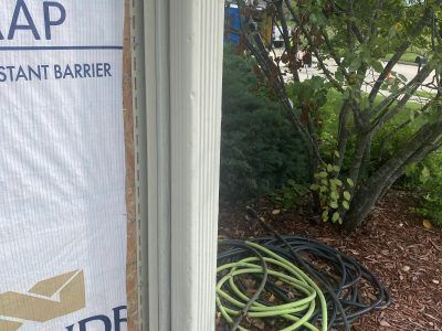 Construction barrier next to a shrub with coiled black and green hoses on mulch
