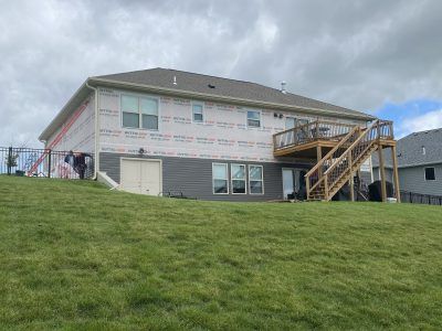 House under construction on a grassy hill under a cloudy sky