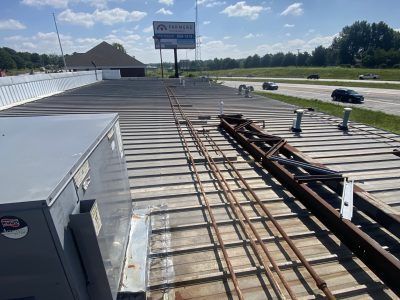 Rooftop with stacked metal beams beside a highway under a partly cloudy sky