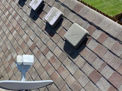 Roof with satellite dish and three vent caps on gray shingles