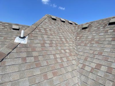 Rooftop with gray shingles, two sloped sections, and a blue sky above
